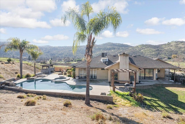 rear view of house featuring a swimming pool with hot tub, a mountain view, and a patio