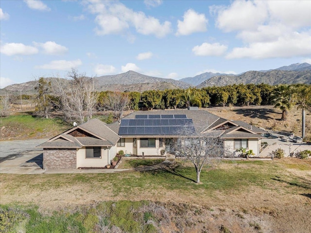 exterior space with a mountain view, a yard, and solar panels