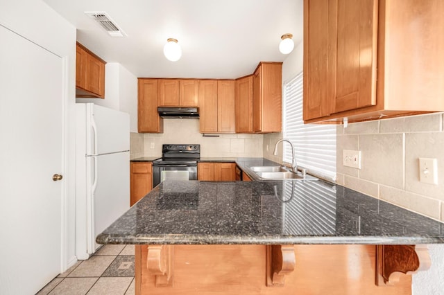 kitchen with electric stove, a breakfast bar, kitchen peninsula, and white fridge