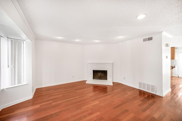 unfurnished living room with ornamental molding, hardwood / wood-style floors, a textured ceiling, and a fireplace