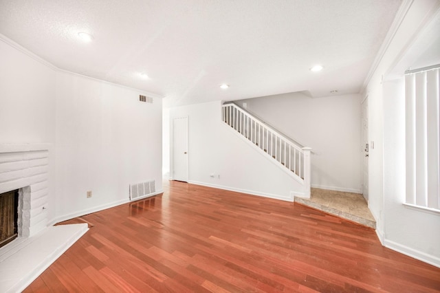 unfurnished living room with wood-type flooring and a brick fireplace