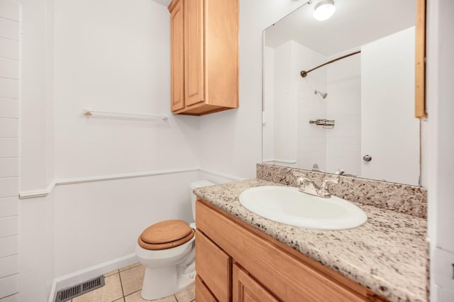 bathroom with tile patterned flooring, vanity, toilet, and a tile shower