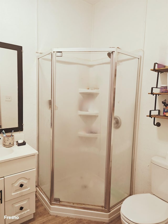 bathroom featuring an enclosed shower, vanity, hardwood / wood-style floors, and toilet