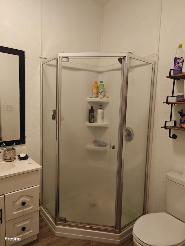 bathroom with walk in shower, vanity, toilet, and hardwood / wood-style flooring