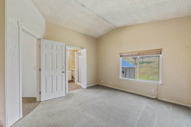 unfurnished bedroom featuring light colored carpet, lofted ceiling, ensuite bathroom, and a textured ceiling