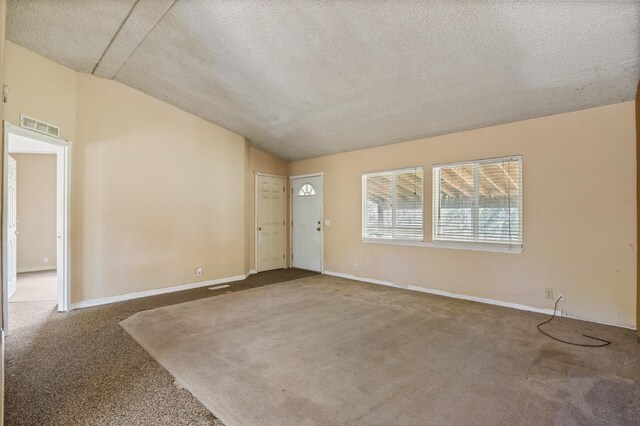 interior space with vaulted ceiling, carpet, and a textured ceiling