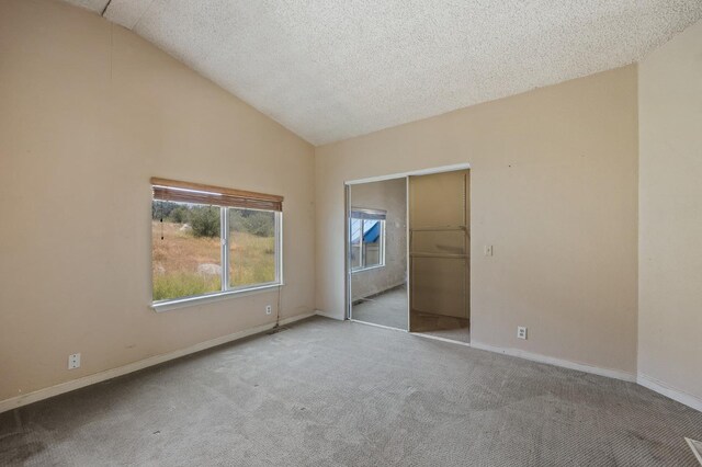 unfurnished bedroom featuring lofted ceiling, light carpet, and a textured ceiling