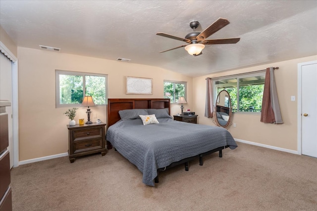 carpeted bedroom with multiple windows, vaulted ceiling, ceiling fan, and a textured ceiling