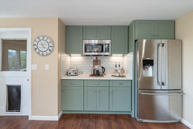 kitchen featuring backsplash, green cabinets, dark wood-type flooring, and appliances with stainless steel finishes