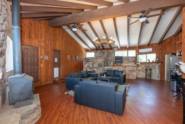 living room featuring wood-type flooring, wood walls, beamed ceiling, and a wood stove