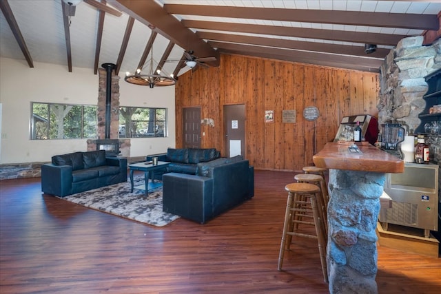 living room with beamed ceiling, a wood stove, dark wood-type flooring, and wood walls