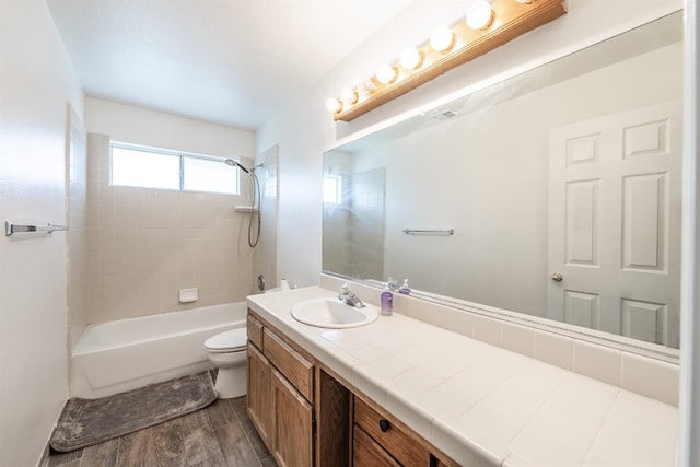 full bathroom with vanity, hardwood / wood-style flooring, toilet, and tiled shower / bath combo