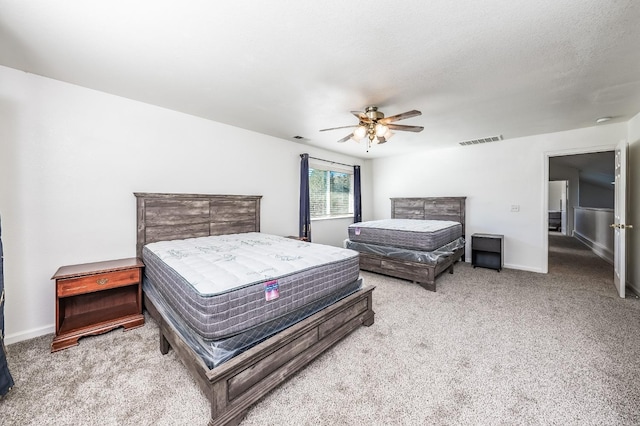 bedroom with ceiling fan, light colored carpet, and a textured ceiling