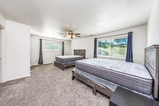 bedroom with ceiling fan, light colored carpet, and a textured ceiling