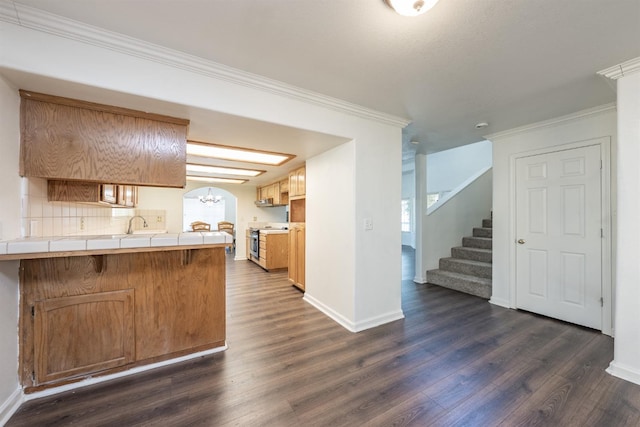 kitchen with tile countertops, ornamental molding, kitchen peninsula, dark wood-type flooring, and stainless steel range oven