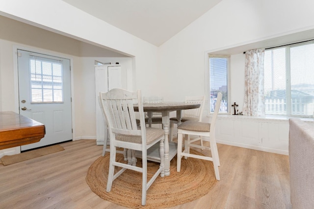 dining area featuring light hardwood / wood-style flooring, vaulted ceiling, and plenty of natural light