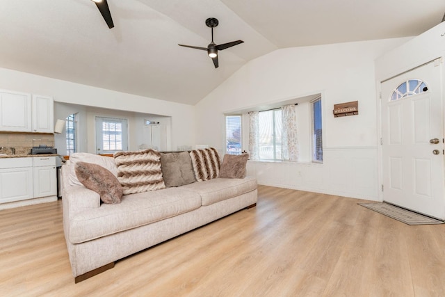 living room with ceiling fan, light hardwood / wood-style floors, and vaulted ceiling