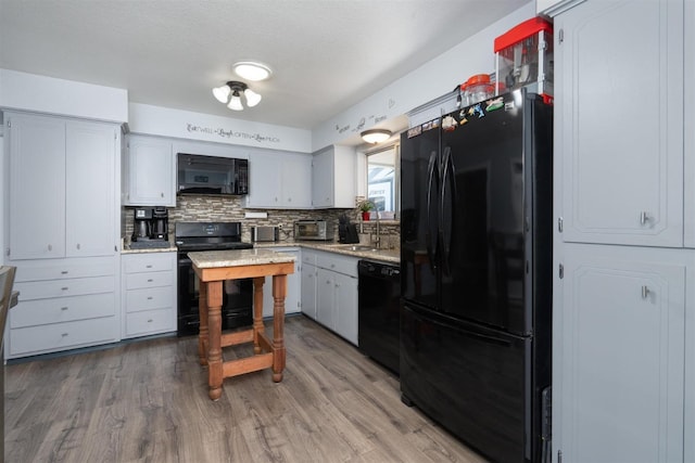 kitchen featuring tasteful backsplash, hardwood / wood-style flooring, sink, and black appliances