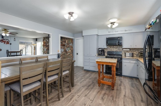 kitchen with hardwood / wood-style flooring, ceiling fan, gray cabinetry, backsplash, and black appliances