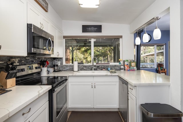 kitchen with white cabinetry, stainless steel appliances, sink, and light stone counters