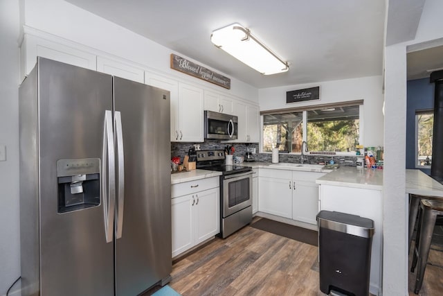 kitchen featuring sink, appliances with stainless steel finishes, backsplash, white cabinets, and dark hardwood / wood-style flooring