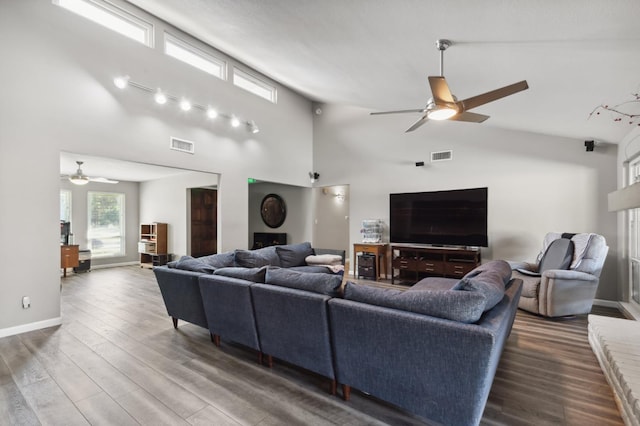 living room featuring dark wood-type flooring, high vaulted ceiling, and ceiling fan