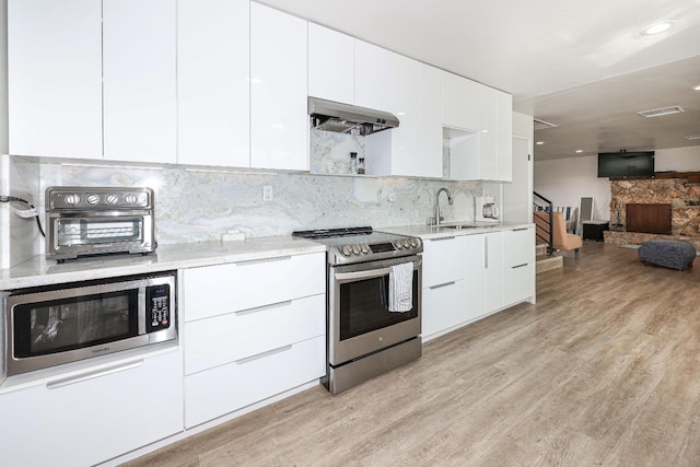 kitchen featuring sink, ventilation hood, stainless steel appliances, light hardwood / wood-style floors, and white cabinets