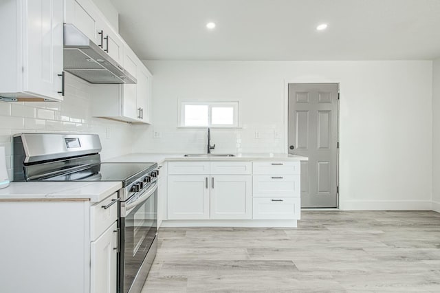 kitchen featuring tasteful backsplash, sink, stainless steel range with electric cooktop, and white cabinets