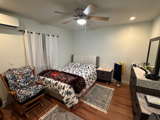 bedroom featuring ceiling fan, hardwood / wood-style floors, and a wall unit AC