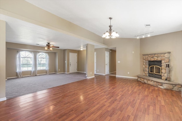 unfurnished living room featuring hardwood / wood-style flooring, a stone fireplace, and ceiling fan with notable chandelier