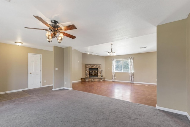 unfurnished living room with ceiling fan with notable chandelier, a fireplace, and carpet flooring