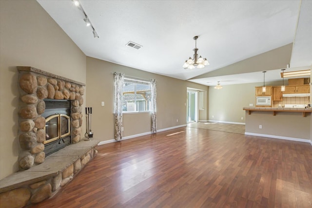 unfurnished living room with lofted ceiling, dark hardwood / wood-style floors, an inviting chandelier, and a fireplace