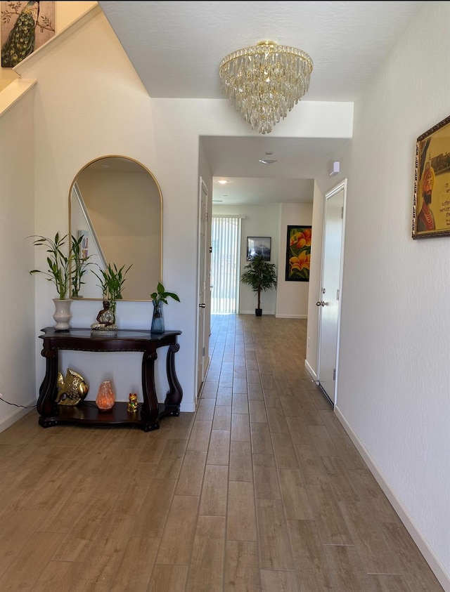 hallway featuring hardwood / wood-style floors and an inviting chandelier