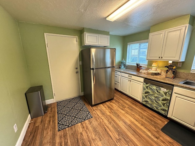 kitchen with white cabinets, stainless steel fridge, light hardwood / wood-style floors, and black dishwasher