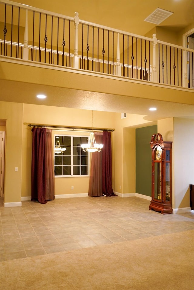 unfurnished living room featuring an inviting chandelier, carpet flooring, and a high ceiling