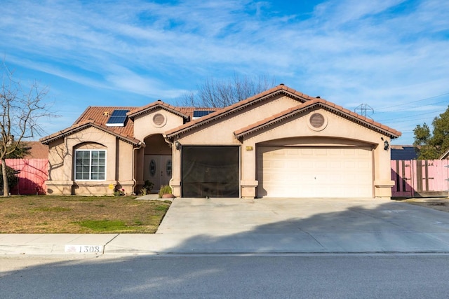 mediterranean / spanish home with a garage, a front yard, and solar panels