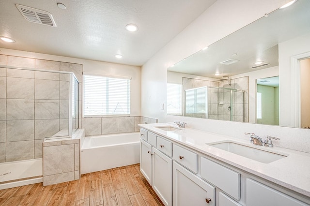 bathroom featuring vanity, hardwood / wood-style flooring, plus walk in shower, and a textured ceiling