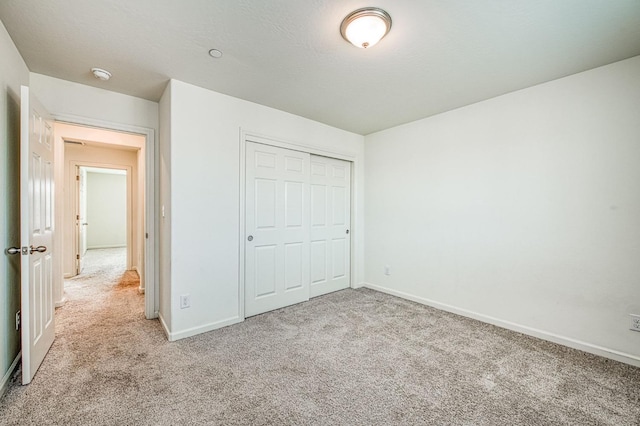 unfurnished bedroom with light carpet and a closet