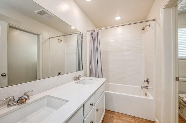 full bathroom featuring wood-type flooring, vanity, shower / bathtub combination with curtain, and toilet