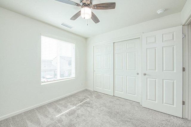 unfurnished bedroom featuring ceiling fan, light colored carpet, and a closet