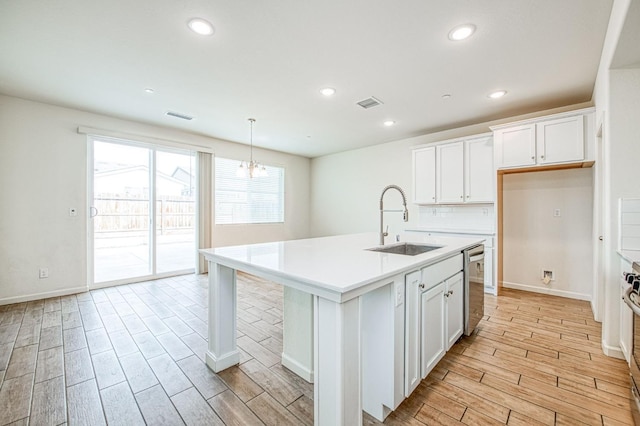 kitchen with pendant lighting, sink, white cabinetry, stainless steel appliances, and a center island with sink