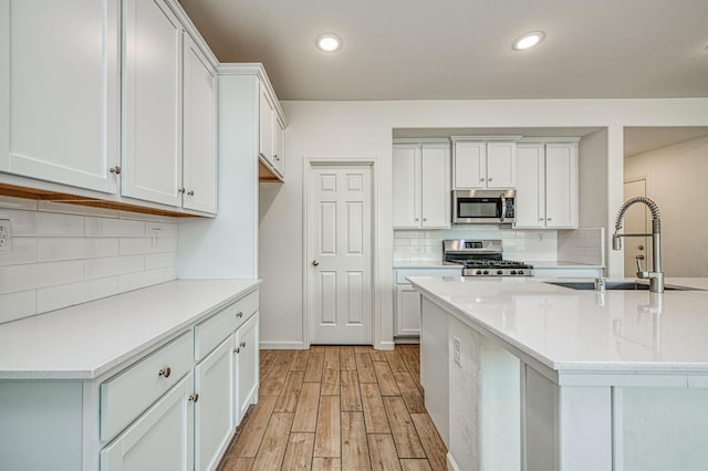 kitchen with sink, white cabinetry, stainless steel appliances, light hardwood / wood-style floors, and decorative backsplash