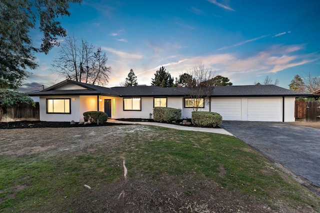 ranch-style home featuring a garage and a yard