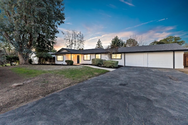 single story home featuring a garage and a lawn