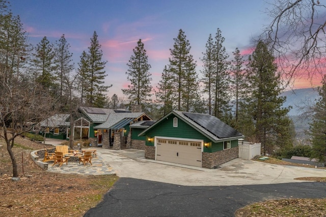 craftsman-style house featuring a garage, a fire pit, and solar panels