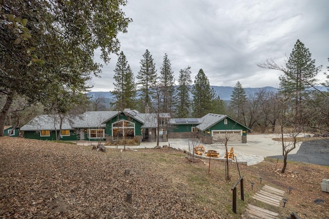 exterior space featuring a garage, a mountain view, and solar panels