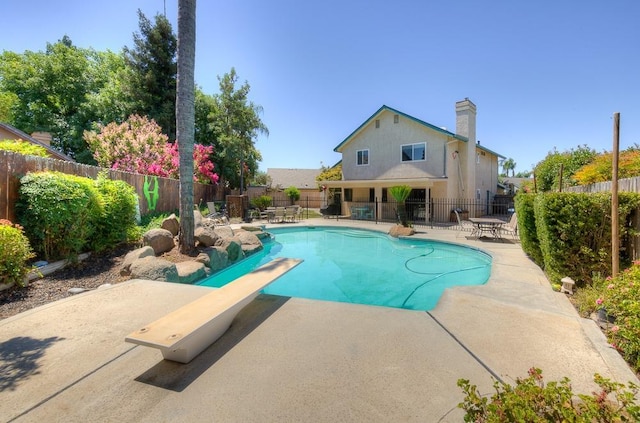 view of pool with a diving board and a patio