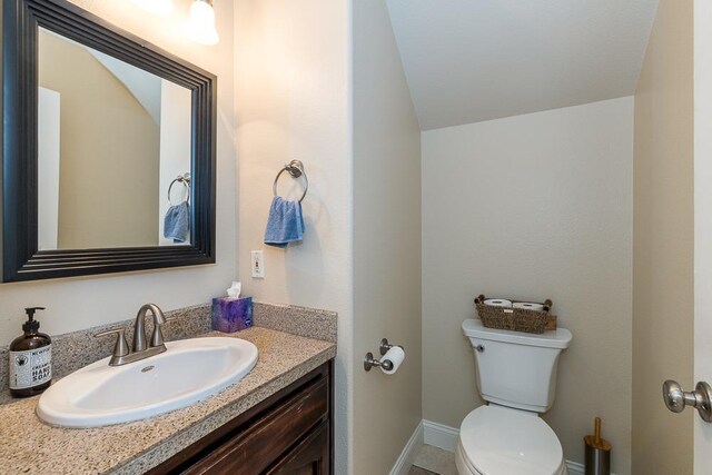 1147 N Carey Ave, Clovis, CA 93611 - bathroom featuring vanity, toilet, lofted ceiling, and baseboards