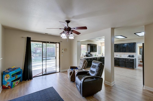 living room with light hardwood / wood-style flooring and ceiling fan