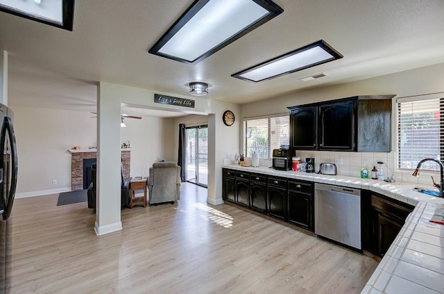 1147 N Carey Ave, Clovis, CA 93611 - kitchen featuring stainless steel dishwasher, tile counters, a sink, light wood finished floors, and ceiling fan